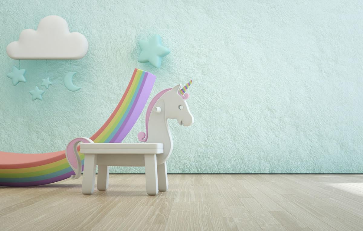 White toy unicorn on wooden floor of kids room with empty rough blue concrete texture wall background.