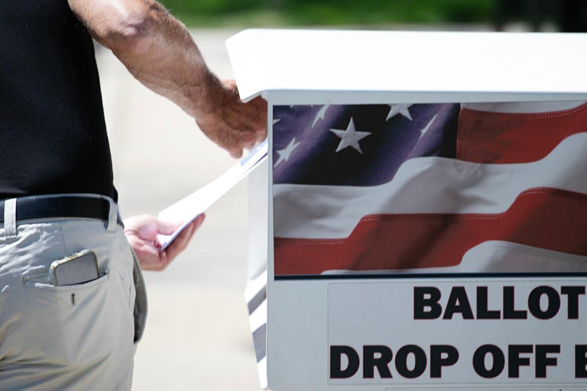 A voter drops off their ballot at a drop box (copy)