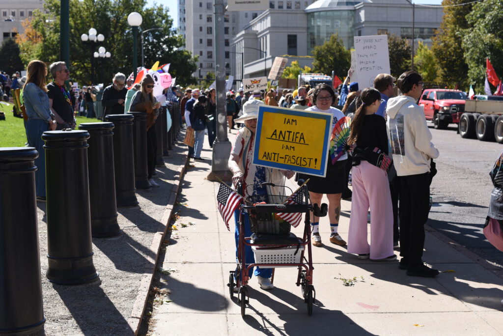 Protestors with signs walk along a street in downtown Denver.