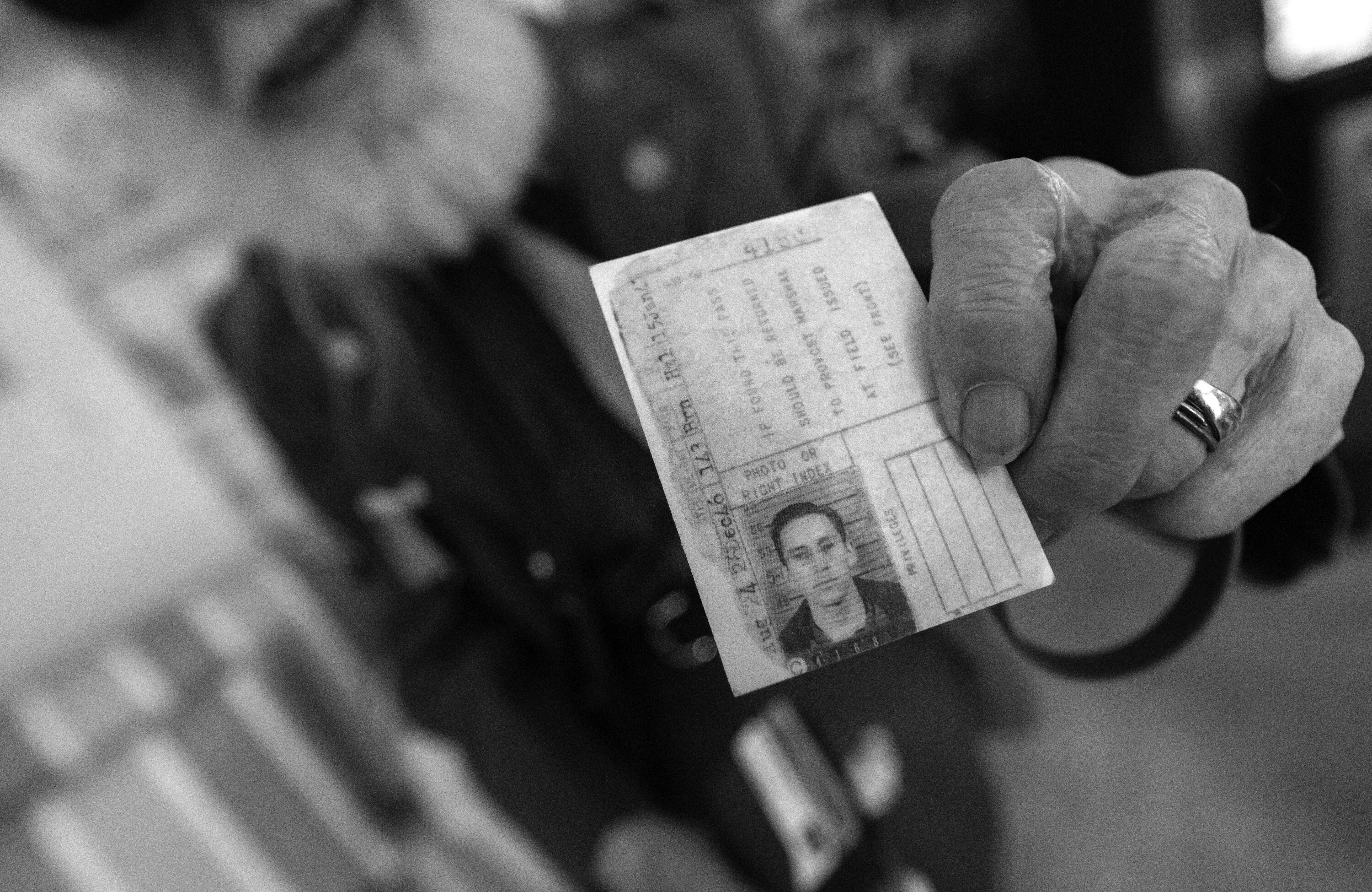 A World War II veteran hols up his Army ID card from 1946.