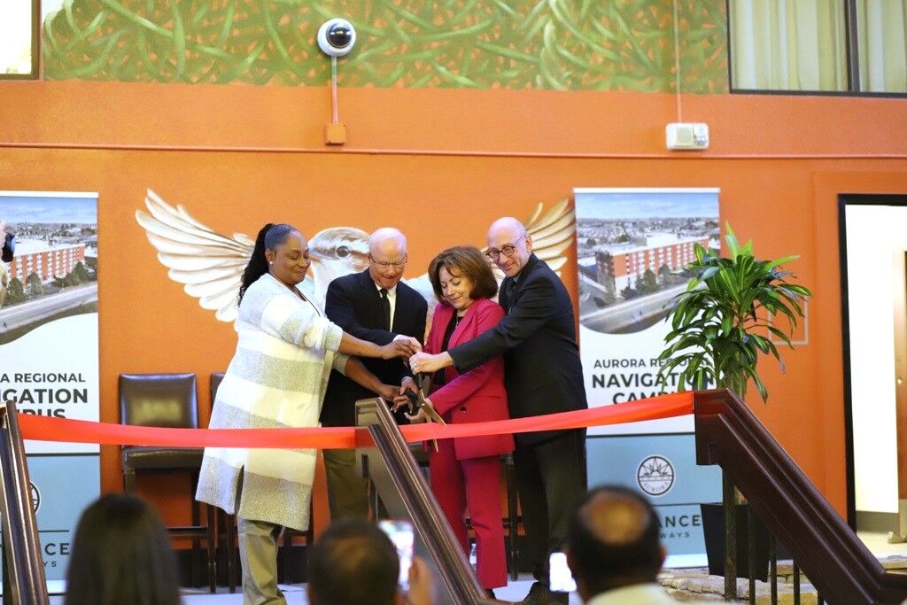 Four people cut a ribbon in a ceremony to celebrate the opening of the Aurora Regional Navigation Campus.