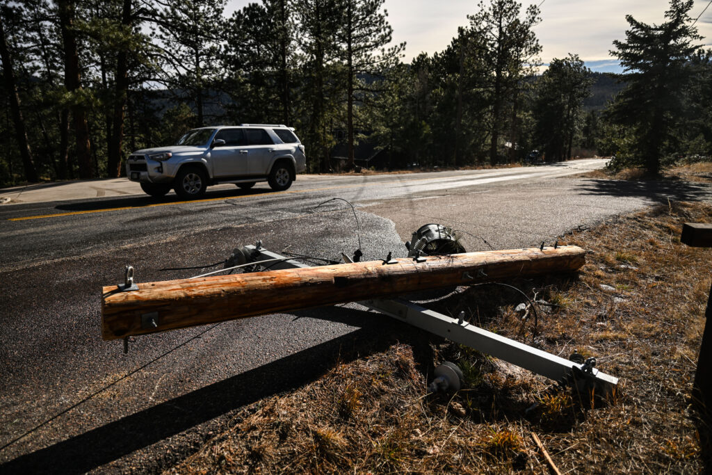 Power lines lay on the ground as a car drives past