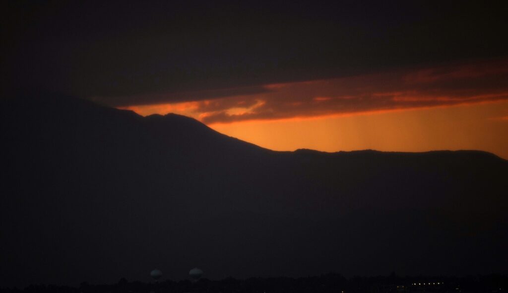 The sky turns golden as the sun sets behind the Rocky Mountains late Wednesday, July 12, 2023, in Commerce City, Colo. (AP Photo/David Zalubowski)