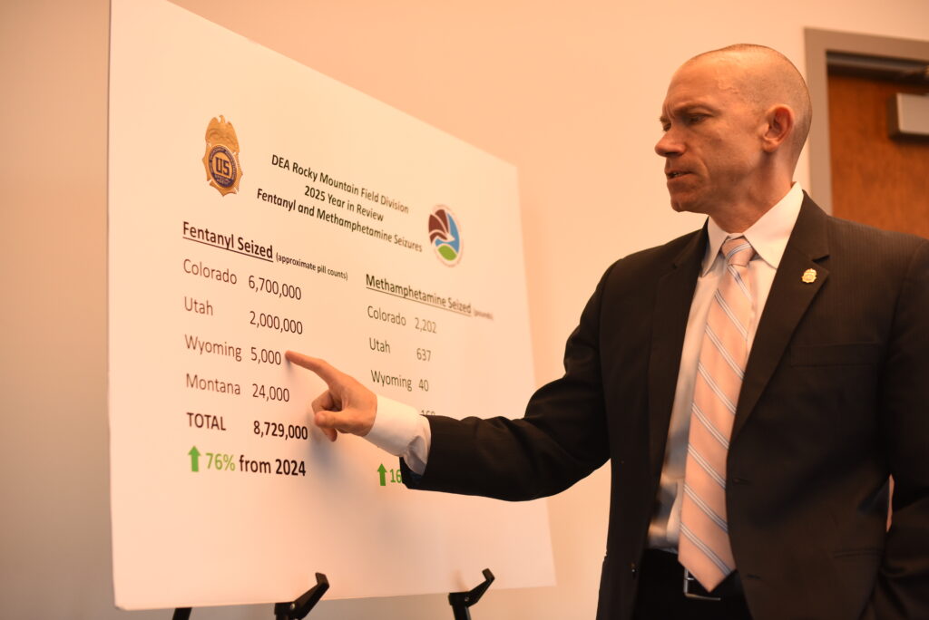 A man in a suit points to data on a board