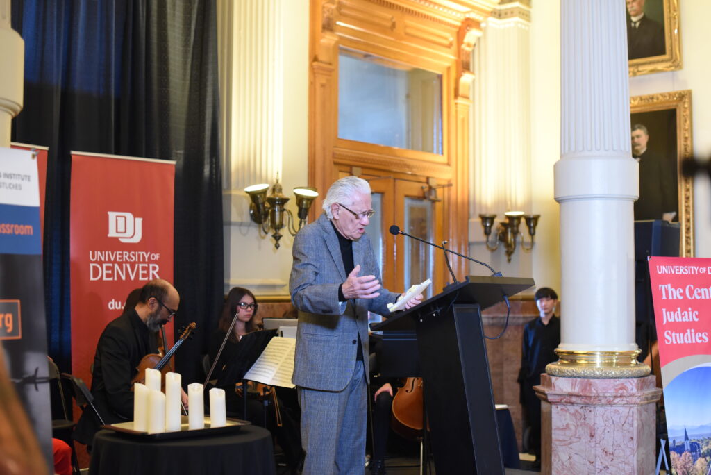 A man speaks at a podium under florescent lighting
