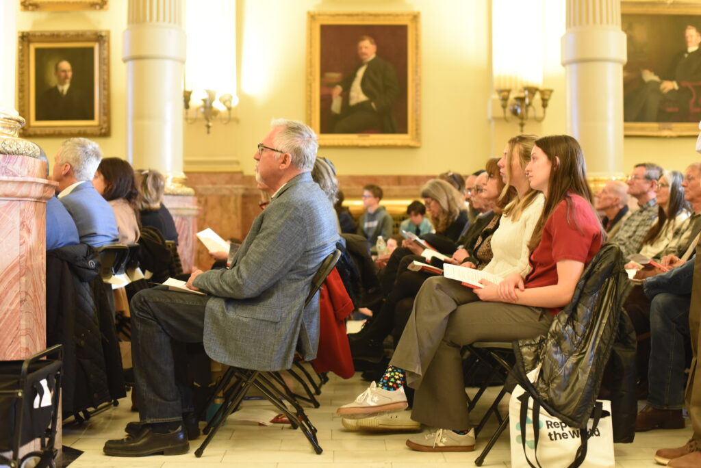 People sit in folding chairs under florescent lighting