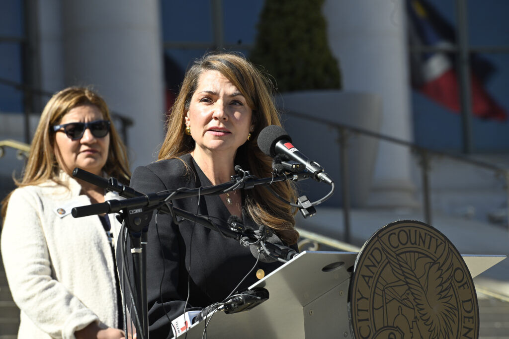 a woman standing at a podium in front of a city government building
