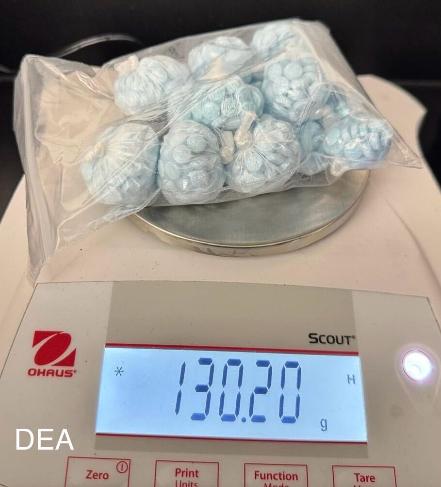 A baggie of blue pills on a scale