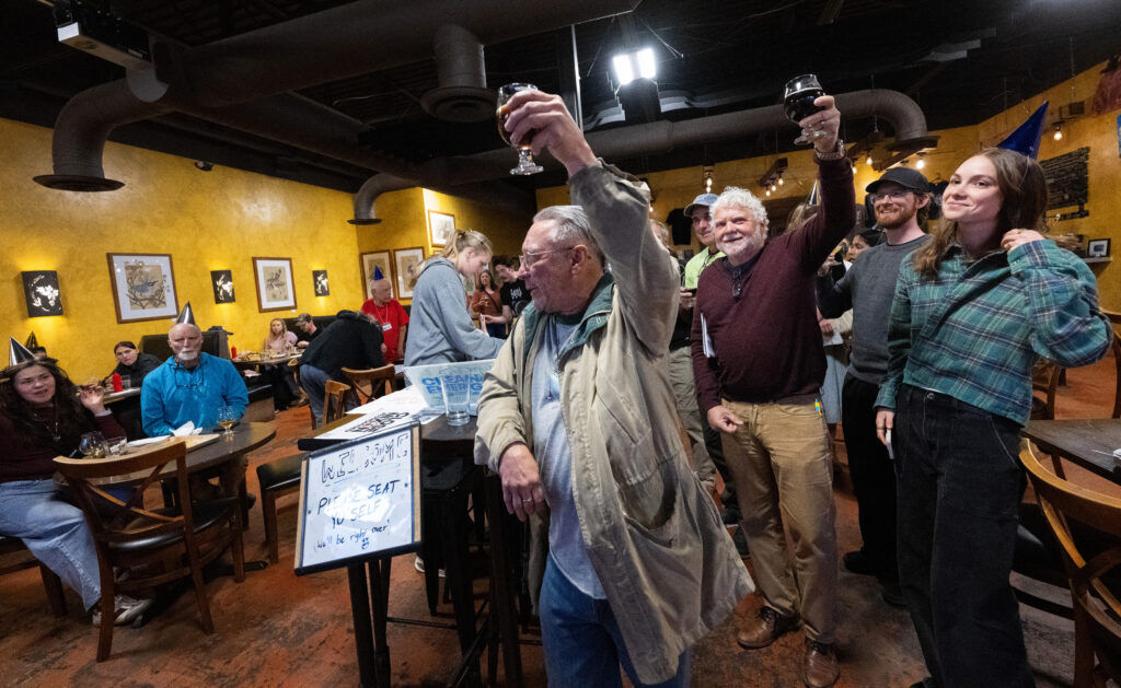 A small group raising a glass for a toast at OCC Brewing