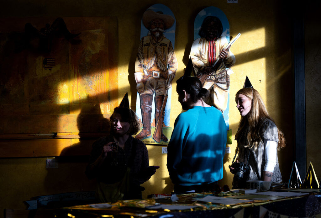 Three people from the Sierra Club wearing party hats in the shadows of OCC Brewing