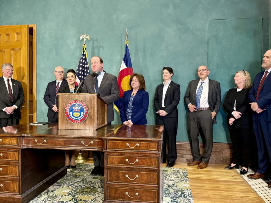 Gov. Jared Polis, Chief Judge Susan Blanco at left, and Lt. Gov. Dianne Primavera at right, hold a press conference at the Colorado Capitol on Feb. 17, 2026 to announce Blanco's appointment to the Colorado Supreme Court. From left to right are Justices Richard L. Gabriel, Brian D. Boatright, Chief Justice Monica M. Márquez, and Justices Carlos A. Samour Jr, Maria E. Berkenkotter and William W. Hood III. (Michael Karlik, Colorado Politics)