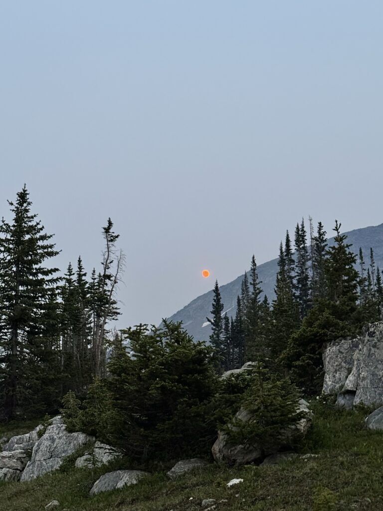 A red moon over hazy mountains caused by wildfire smoke.