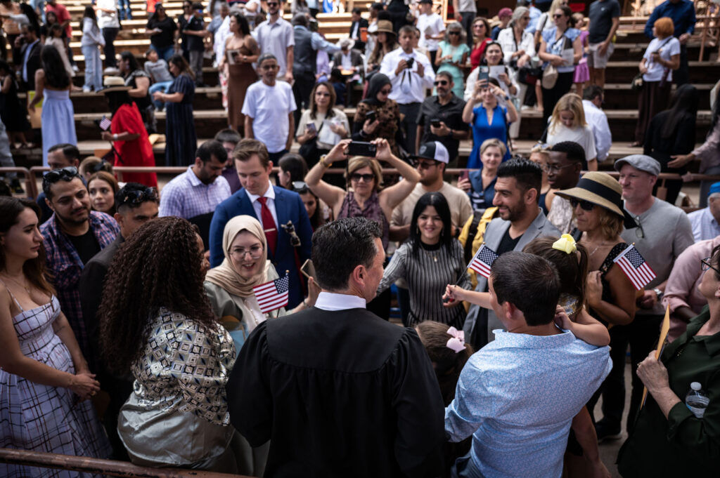U.S. District Court Chief Judge Daniel D. Domenico takes photos with new citizens following a naturalization ceremony at Red Rocks on Thursday, July 30, 2026 in Morrison, Colo.