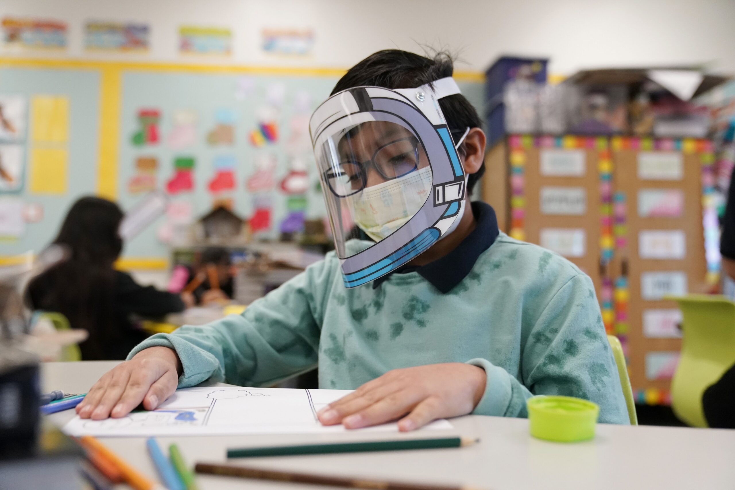 FILE - A student wears a mask and face shield in a 4th grade class amid the COVID-19 pandemic at Washington Elementary School on Jan. 12, 2022, in Lynwood, Calif. Four years after the COVID-19 pandemic closed schools and upended child care, the CDC says parents can start treating the virus like other respiratory illnesses.