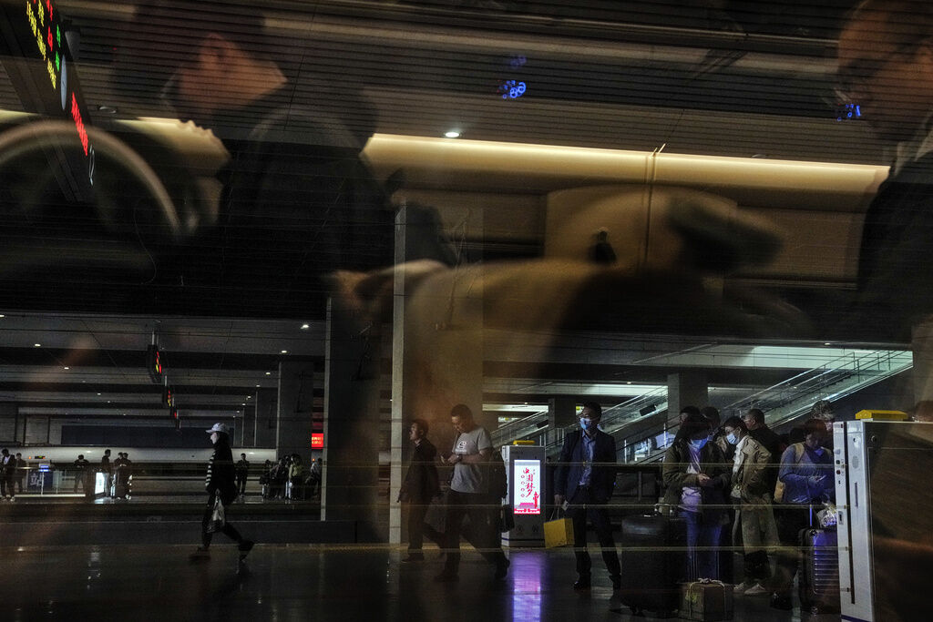 Passengers, some wearing face masks wait for their train at a railway station in Wuhan, central China's Hubei province, Monday, May 8, 2023. China's top official in charge of COVID-19 pandemic prevention said the country will remain vigilant against the virus and push forward vaccination after the World Health Organization declared COVID-19 no longer qualifies as a global emergency. (Andy Wong, The Associated Press)