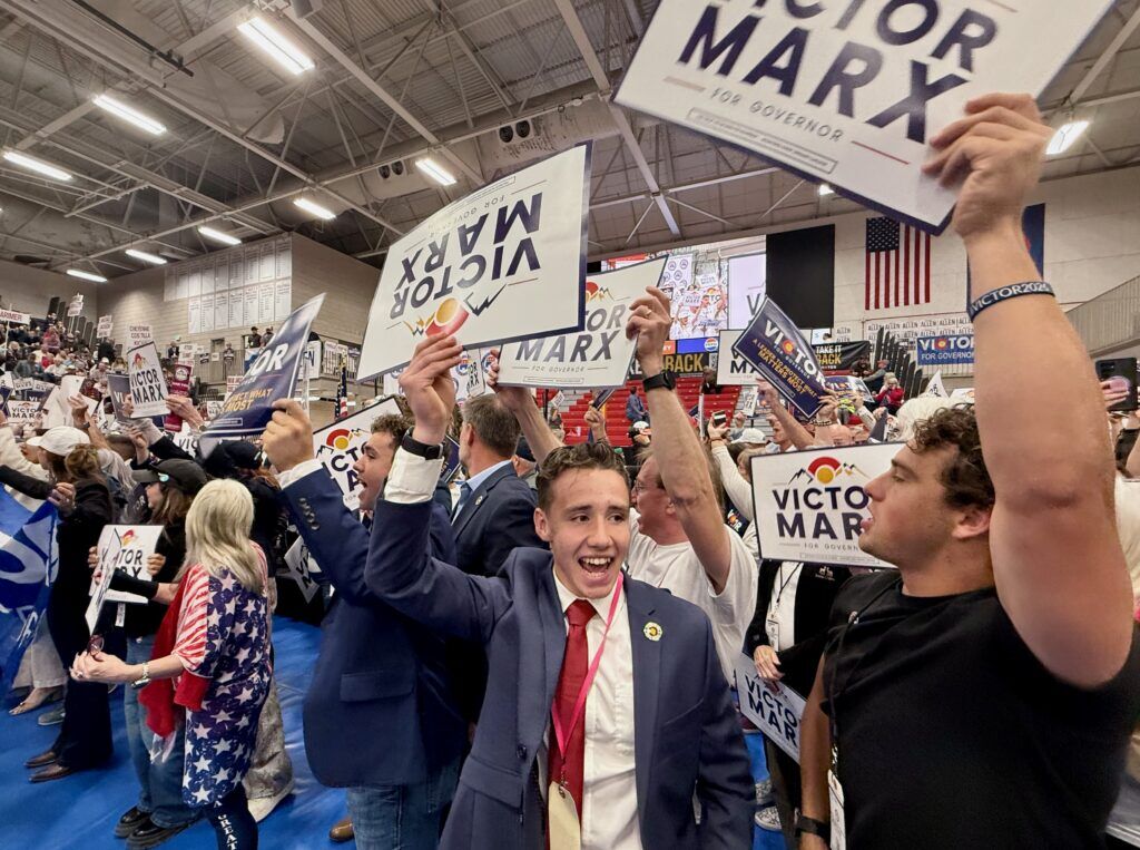 Supporters of Republican gubernatorial candidate Victor Marx wave signs as he takes the stage at the Colorado GOP's state assembly on Saturday, April 11, 2026, at Massari Arena on the Colorado State University Pueblo campus in Pueblo. (Ernest Luning/Colorado Politics)