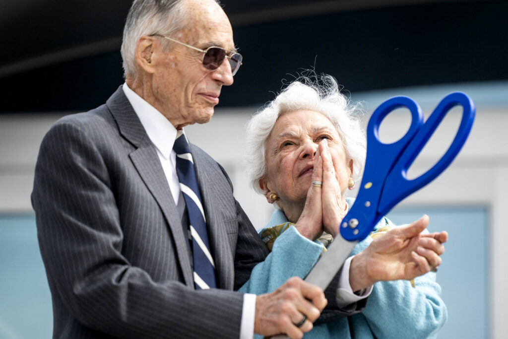 Zita Hosmer smiles and and looks to the sky with her hands clasped in prayer as she stands next to her husband, Gen. Bradley Hosmer, left following the ribbon cutting ceremony for The General Bradley and Zita Hosmer Visitor Center during a dedication ceremony in Colorado Springs on Friday, May 15, 2026. (The Gazette, Michael G. Seamans)