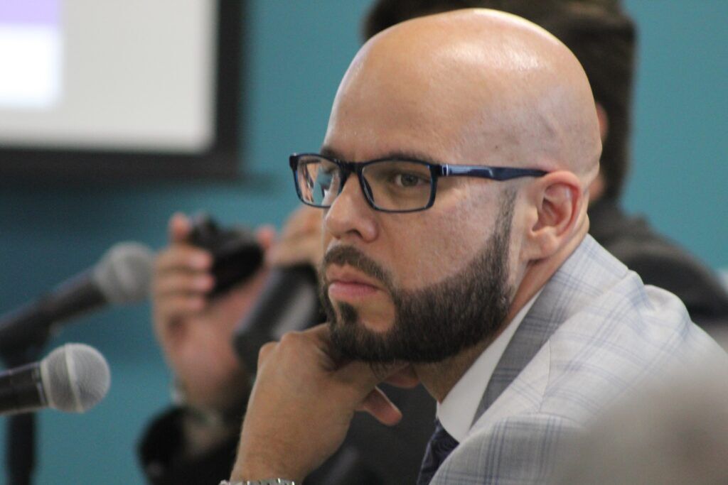 Denver Public Schools Superintendent Alex Marrero, wearing glasses and a light-colored suit, rests his chin on his hand while listening during a Board of Education meeting Aug. 13, 2026.