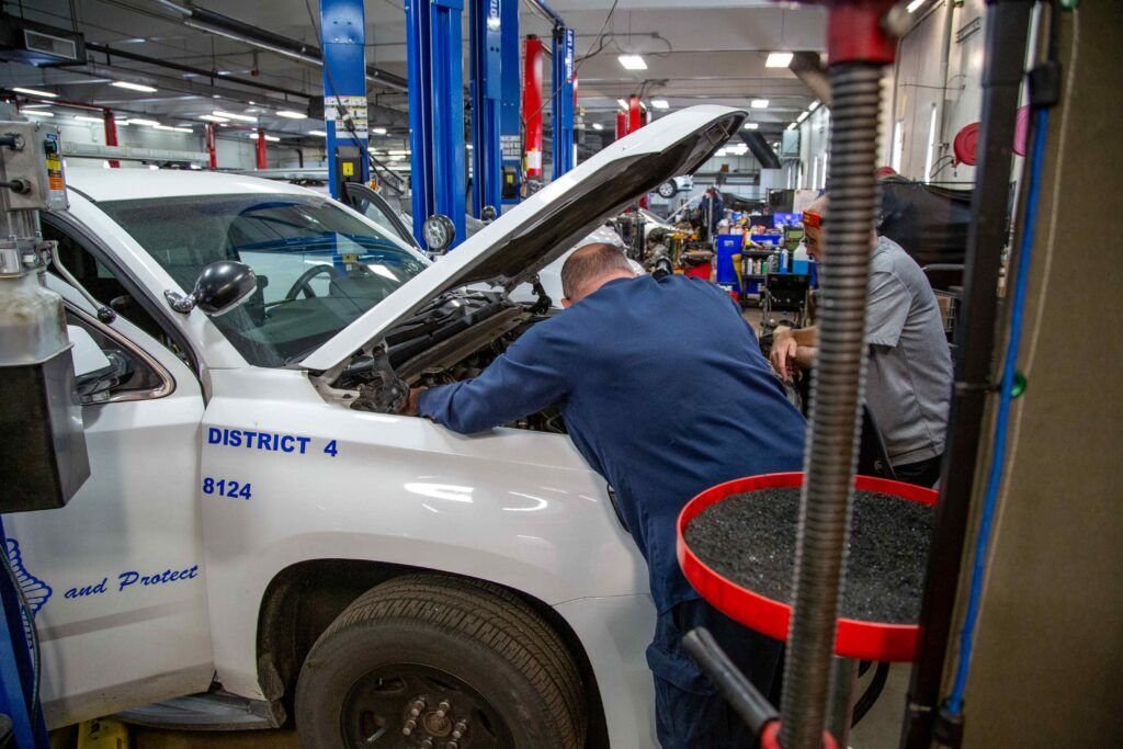 a mechanic looks inside of the engine of a police car