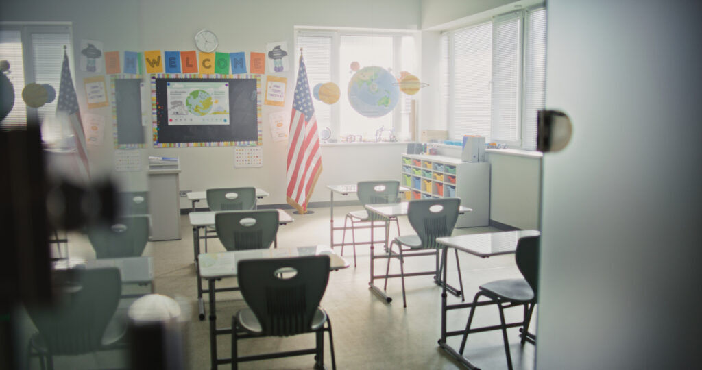 Interior of Modern Empty Classroom with Desks for Students, Chalkboard, Hanging Models of Solar System and Colorful Posters.