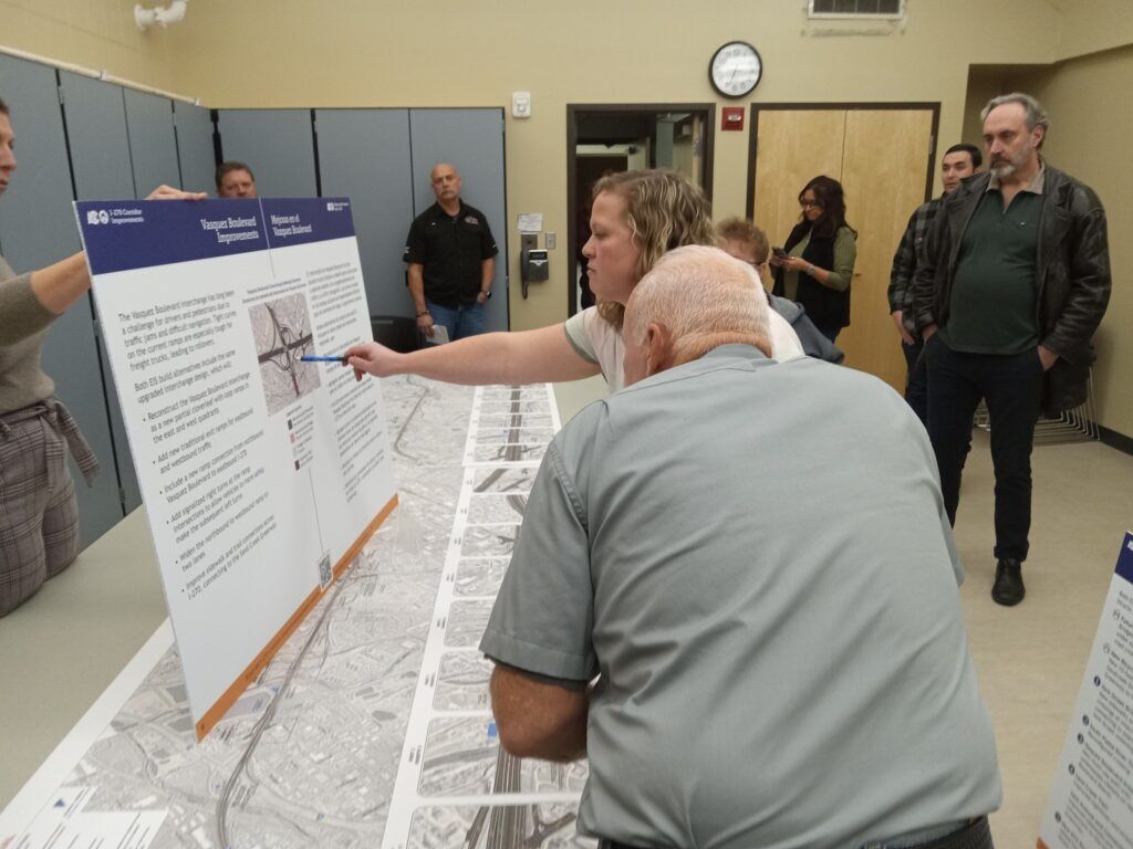 A person points to a poster board during a meeting about the I-270 corridor.